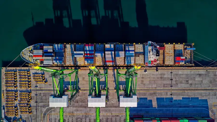 Aerial view of a container ship alongside gantry cranes at a container terminal, illustrating Red Sea and Suez Canal shipping capacity in 2026